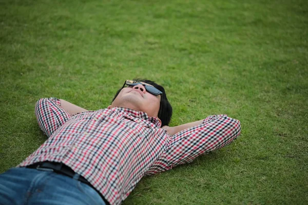 Man Liggend Groen Gras Een Schaakshirt Blauwe Jeans Een Park — Stockfoto