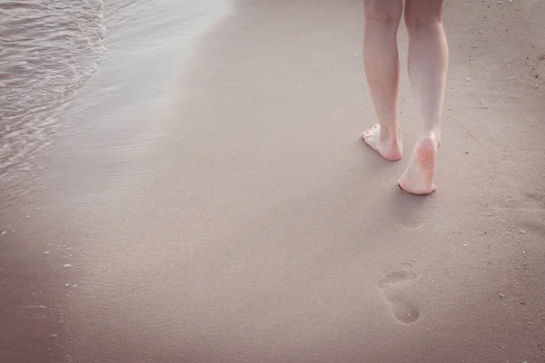 ビーチトラベルだけで 女性だけで砂のビーチで砂の中に足跡を残し歩く女性の足と黄金の砂の背景のクローズアップ詳細 — ストック写真