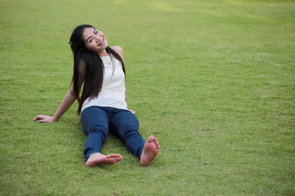宽松的女人躺在绿草上 蓝色牛仔裤在绿草的衬托下 — 图库照片