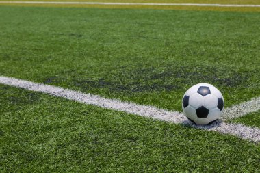Futbol topu yeşil futbol sahasının arka planında beyaz çizgide