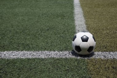 Futbol topu yeşil futbol sahasının arka planında beyaz çizgide
