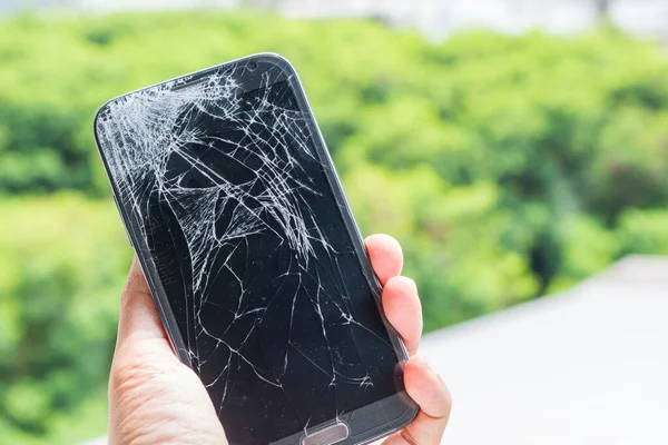 Zemine akıllı telefon düşüşü ve elinde yeşil bokeh arka planıyla kırılan ekran hasarı