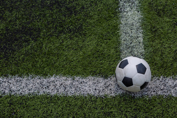 soccer ball on the white line on green soccer field grass background