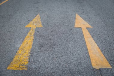 İki sarı ok eski ve asfalt yol arka planında yeni yön