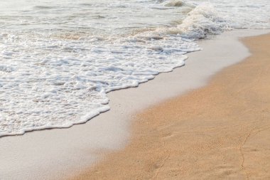 Kumlu sahil arka planında denizin beyaz su dalgası