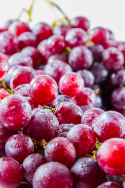 Beyaz zemin üzerinde su damlası olan taze kırmızı üzüm.