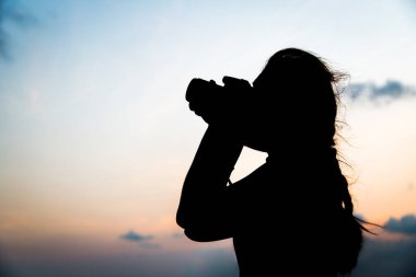 Siluet fotoğrafçısı gün batımında fotoğraf çekiyor.