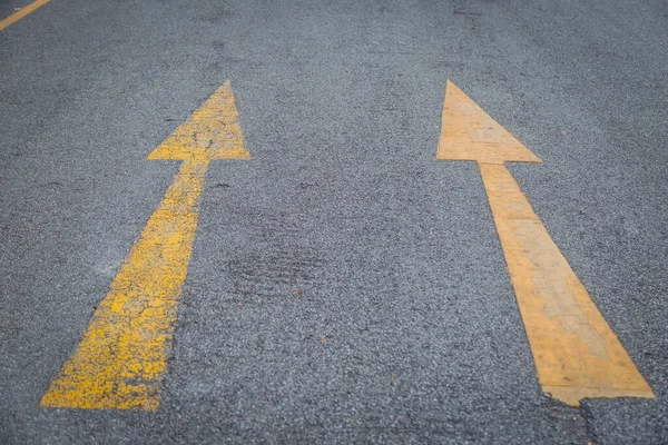 Two yellow arrows old and new  directionon asphalt road background