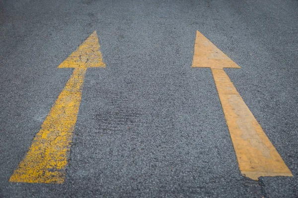 Two yellow arrows old and new  directionon asphalt road background