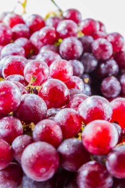 Beyaz zemin üzerinde su damlası olan taze kırmızı üzüm.