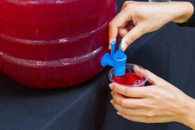 Kırmızı sıvı içecek arka planına sahip su bardağını tutan kadın.