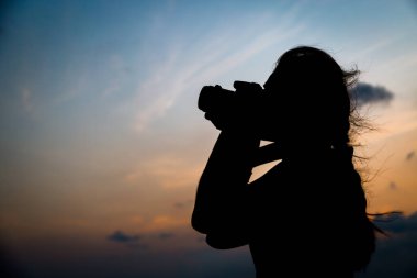 Siluet fotoğrafçısı gün batımında fotoğraf çekiyor.