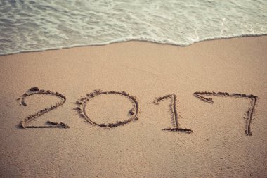 Plaj arka planında kuma yazılmış klasik tarz 2017 mesajı