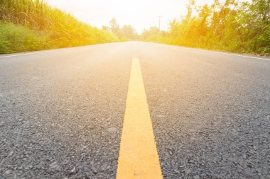 Tarımsal tarlalardan geçen boş asfalt yolda sarı çizgiye doğru