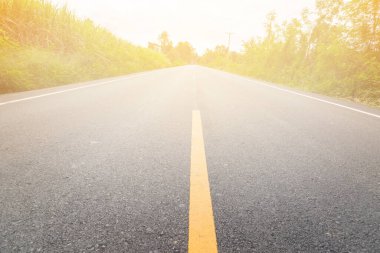 Tarımsal tarlalardan geçen boş asfalt yolda sarı çizgiye doğru