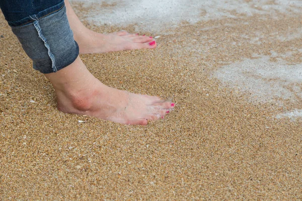 Ženské Nohy Červenou Pedikúrou Nosit Modré Džínové Stojan Pláži Písek — Stock fotografie