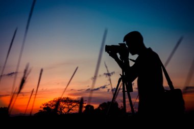 Gün batımı geçmişi olan siluet fotoğrafçı.