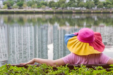 Şapka takan kadınlar parkta oturur ve dinlenirler.