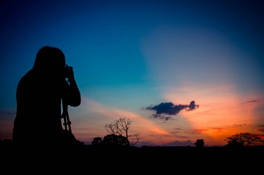 Gün batımı geçmişi olan siluet fotoğrafçı.