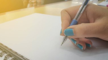 Boş belgelerin arkaplanını kalemle kapatan kadın elleri