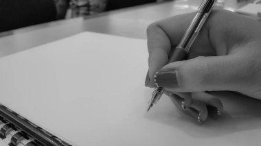 Boş belgelerin arkaplanını kalemle kapatan kadın elleri