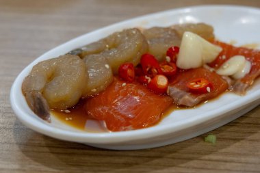 Acı biber ve sarımsakla kaplı taze çiğ karides ve somonla kaplı baharatlı deniz ürünleri tabağı..