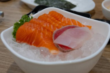 Ezilmiş buz yatağında servis edilen taze somon, ton balığı ve beyaz balıklı deniz ürünleri tabağının yakın çekimi..