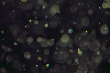 Koyu bir arkaplanda farklı boyut ve renklerde odaklanmış bokeh ışıkları.