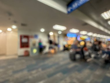 Havaalanının iç kısmının bulanık görüntüsü, hafif ışıklandırma, oturma alanları ve sakin, bastırılmış bir atmosferi var..