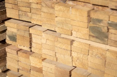 Kereste deposunda istiflenmiş ahşap kalaslar, çeşitli gölgeler ve dokular, düzenli bir şekilde düzenlenmiş..