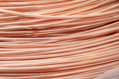 Parlak yüzeyi olan sarmalanmış bakır kabloların yakın çekimi, karmaşık örtüşen desenler, sıcak ışıklandırma..