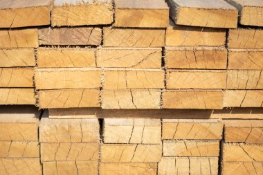 Kereste deposunda istiflenmiş ahşap kalaslar, çeşitli gölgeler ve dokular, düzenli bir şekilde düzenlenmiş..