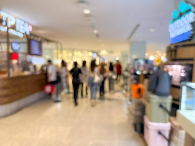 Hareketli bir alışveriş merkezinin bulanık görüntüsü modern bir perakende satış ortamının canlı atmosferini yakalıyor. İnsanlar alışveriş yaparken görülüyor.