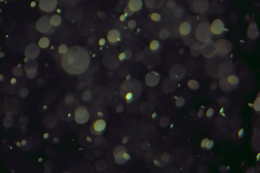 Koyu bir arkaplanda farklı boyut ve renklerde odaklanmış bokeh ışıkları.