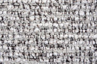 Açık gri ve koyu renkli ipliklerin karışımı sıkıca dokunmuş bir kumaşın yakın çekim görüntüsü ince desenli bir desen oluşturur..