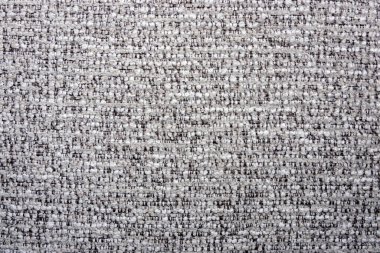 Açık gri ve koyu renkli ipliklerin karışımı sıkıca dokunmuş bir kumaşın yakın çekim görüntüsü ince desenli bir desen oluşturur..