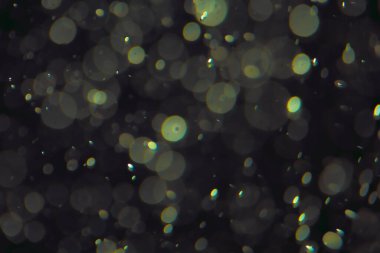 Koyu bir arkaplanda farklı boyut ve renklerde odaklanmış bokeh ışıkları.