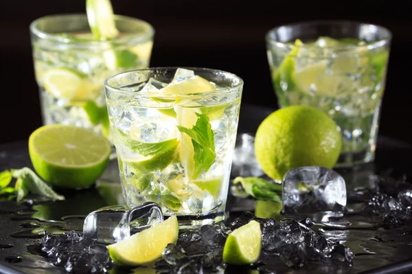 Mojito kireç ve buz karanlık bir arka plan üzerinde kokteyl