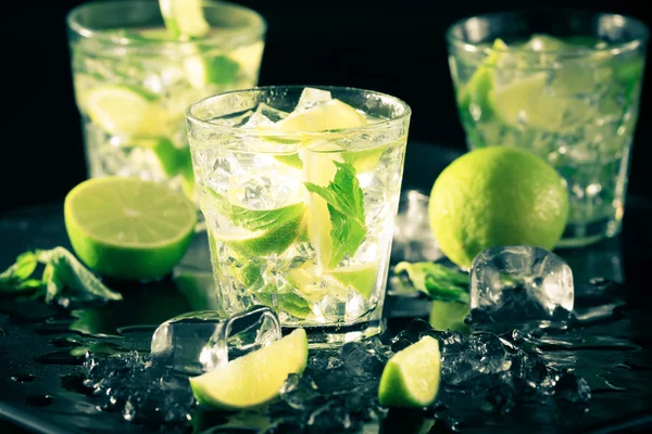 Cóctel Mojito sobre fondo oscuro con lima y hielo —  Fotos de Stock