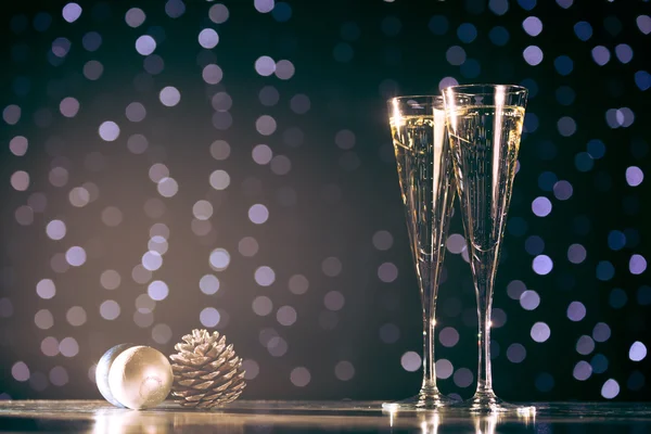 Dwie szklanki szampana z Boże Narodzenie zabawki. Świąteczne oświetlenie bok — Zdjęcie stockowe