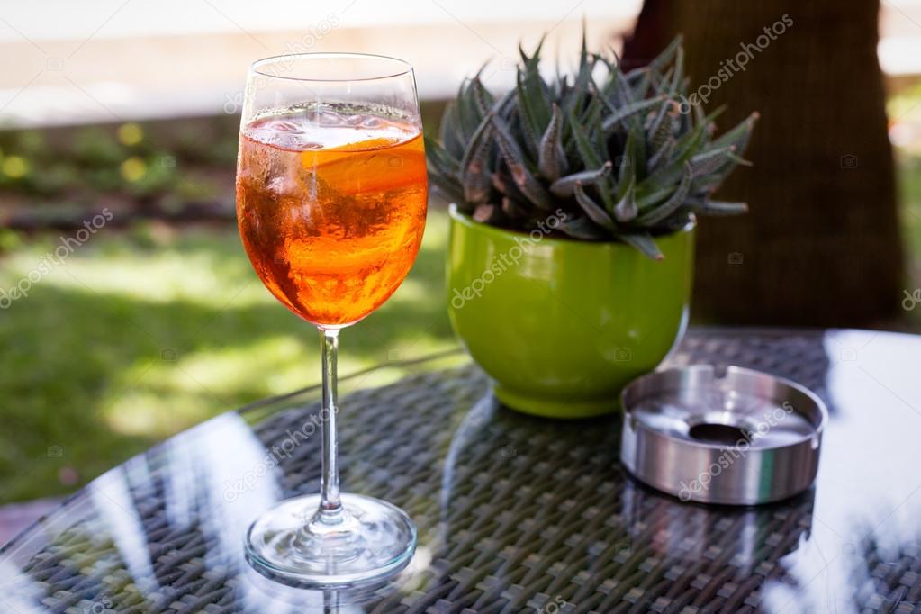 Glass of Aperol Spritz with ashtray and cactus
