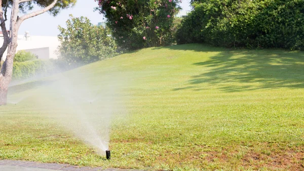 Utomhus sprinkler arbetar på en gröna gräsmattan — Stockfoto