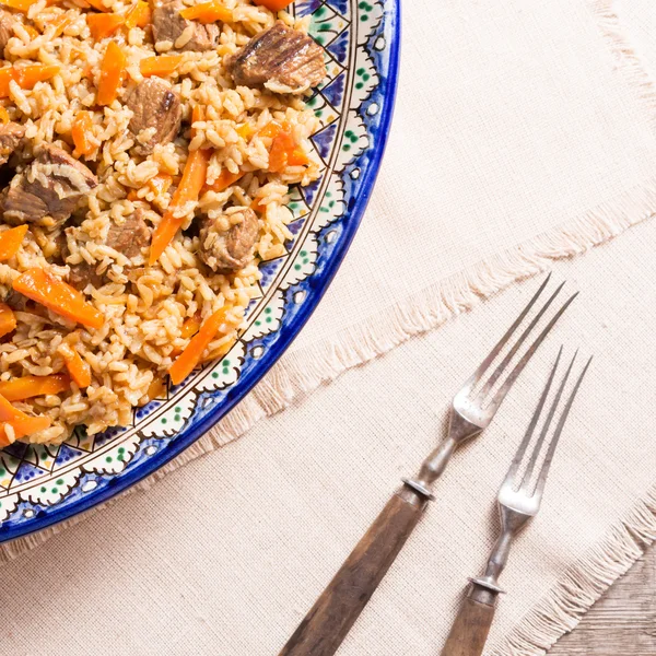 Pilaf in handmade plate on wooden background — Stock Photo, Image