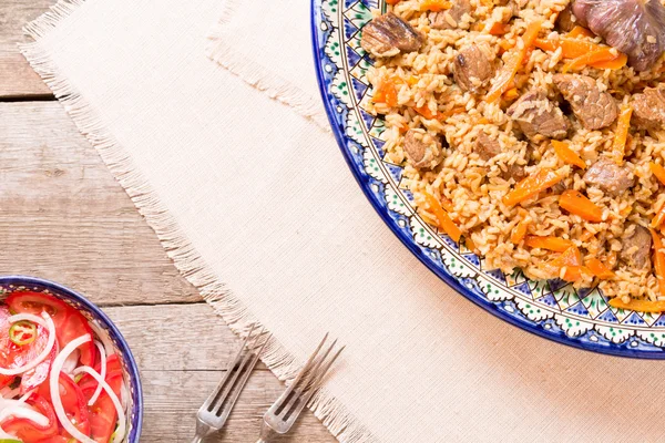 Pilaf and achichuk salad in handmade plate on wooden background — Stock Photo, Image