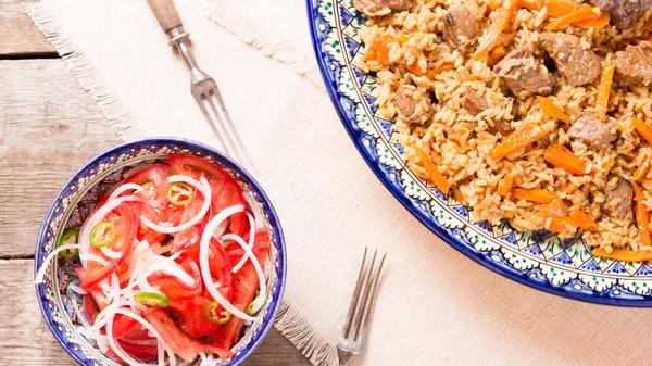 Pilaf and achichuk salad in handmade plate on wooden background — Stock Photo, Image