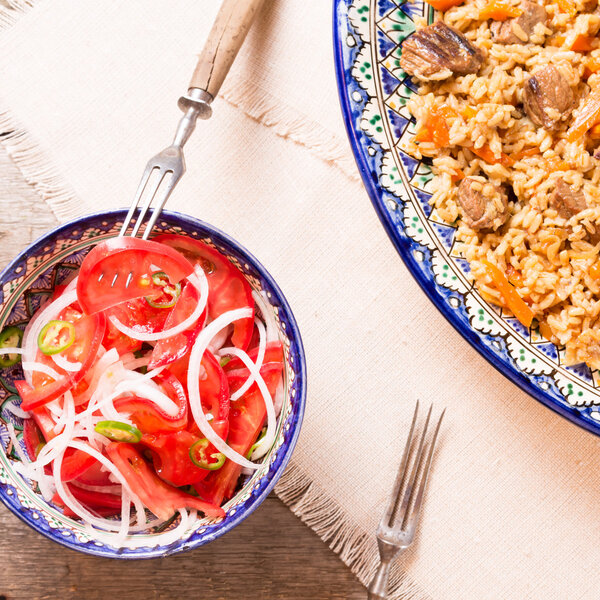 Pilaf and achichuk salad in handmade plate on wooden background