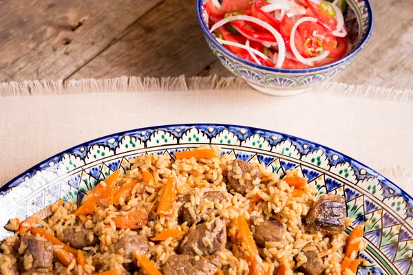 Pilaf and achichuk salad in handmade plate on wooden background — Stock Photo, Image