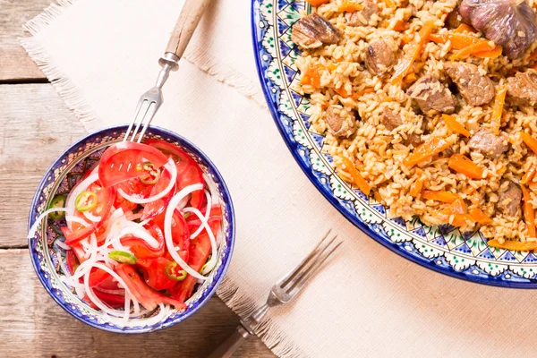 Pilaf and achichuk salad in handmade plate on wooden background — Stock Photo, Image