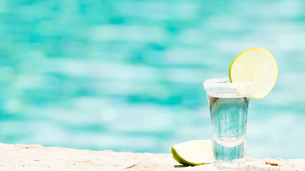 Tequila shot con calce su sfondo blu — Foto Stock