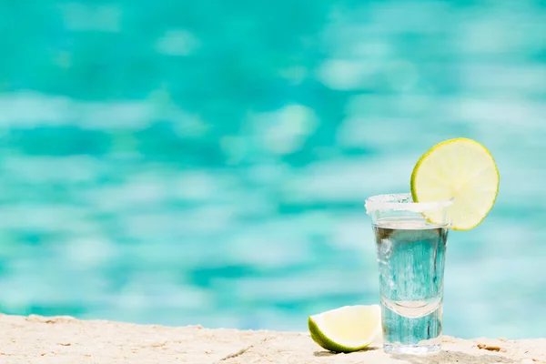 Tequila shot con calce su sfondo blu — Foto Stock